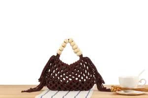 Detailed view of handmade brown woven macrame bag with chic wooden bead handles and fringe.