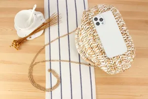 Detail view of the two-tone handmade woven straw cross-body bag in a lifestyle setting.