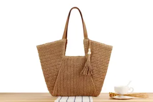 Detailed view of the stylish woven straw tote bag with brown leather handles and chic tassel.