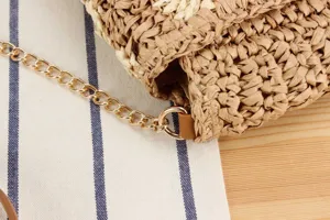 Detailed view of handmade woven straw crossbody bag with gold chain strap for casual summer.