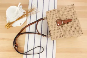 Handwoven straw crossbody bag with brown leather straps and buckle closure, casual beach style.