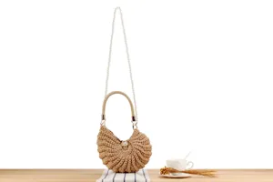 Handmade woven crossbody bag detail showing pearl chain strap and intricate shell shape design.
