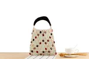Vue détaillée du sac à main tissé beige avec perles colorées et poignée en écaille.