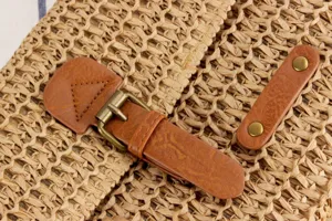 Detailed shot of retro woven straw bag with PU leather buckle and vintage bronze hardware.