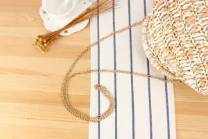 Detail view of round woven straw crossbody bag with two-tone design and gold metal chain.