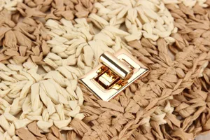 Handcrafted woven straw handbag detail highlighting metallic turn-lock closure and crochet texture.