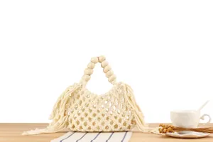 Detail view of the beige woven macrame handbag with wooden bead handle and stylish fringe.