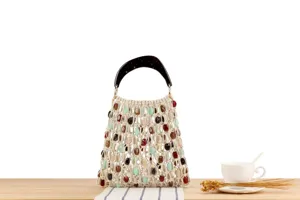 Vue détaillée d'un sac à main tressé avec des perles colorées et poignée sur table.