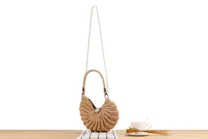 Handmade woven shell handbag detail showing crochet texture, single handle and pearl chain strap.