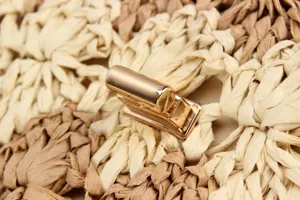 Detail shot of the golden metal turn-lock closure on a handmade woven straw casual handbag.