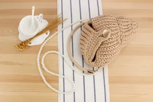 Handcrafted crochet shell handbag detail, chic beige woven beach purse with pearl strap accent.