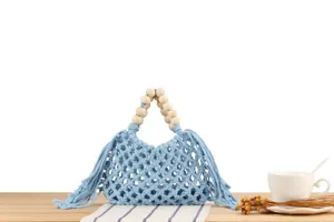 Light blue macrame woven handbag detail showcasing wooden bead handles and fringe accents.