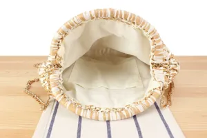 Detail view of a stylish two-color woven straw bucket bag with gold chain and inner pocket.