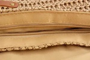 Detailed close-up of a woven straw bag featuring a secure zipper closure and fabric lining.