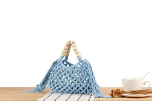 Light blue handmade macrame woven hollow handbag with wooden bead handles and cute tassel details.