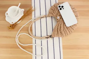 Detailed view of beige handmade crochet crescent shoulder bag with pearl strap setup.