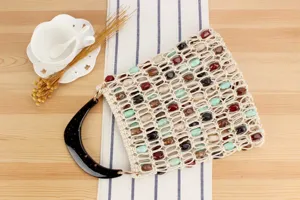 Gros plan sur les détails du sac à main tissé de perles avec des pierres colorées et poignée.