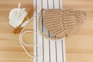 Handmade crochet seashell crossbody bag with pearl strap, chic beach vacation purse style.
