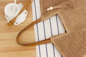 Chic straw woven tote bag detail showing fine texture, brown PU handle and cute tassel decor.