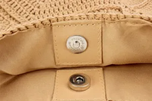 Primo piano di dettaglio della chiusura magnetica interna della borsa di paglia.