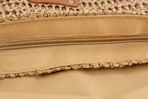 Close-up of straw woven bag zipper and fabric lining, casual minimalist style detail view.
