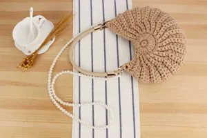 Handmade crochet shell bag detail showing woven texture, leather handle and elegant pearl chain.
