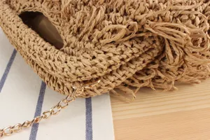 Close-up detail of hand-woven straw bag texture with elegant gold metal chain strap.