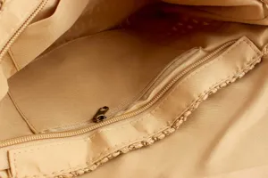 Close-up view showing the interior zipper pocket and smooth lining of the woven bag.