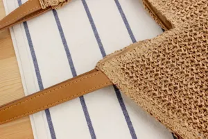 Woven straw handbag detail showing stylish brown PU leather handles and fine texture, casual chic.