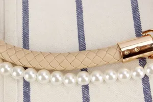 Detailed view of the woven bag strap with faux pearls and gold clasp, elegant craftsmanship.
