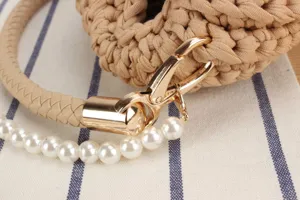 Detail shot of handmade crochet handbag handle featuring golden clasp and elegant pearl strap.