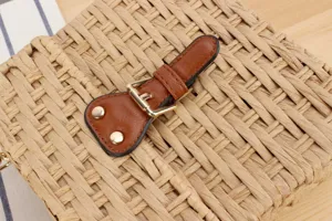 Handmade woven straw bag detail view with brown leather strap and metal buckle for beach