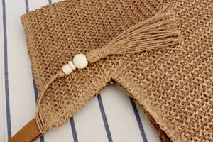 Woven straw handbag detail with chic tassel and wooden beads for casual summer beach vacation.