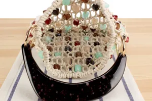 Détail de l'intérieur du sac seau tissé à la main avec des perles colorées et des poignées.