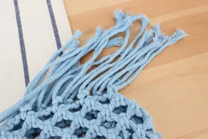 Blue woven macrame bag detail, textured fringe and hollow knit pattern for summer beach wear.