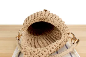 Close up view of beige handmade woven handbag detail, featuring gold hardware and pearl strap.