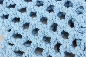 Close-up detail of light blue woven macrame bag mesh texture, premium craftsmanship material.