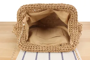 Detailed interior view of handmade woven straw bag featuring beige lining and gold chain.