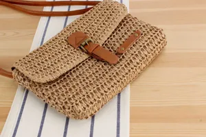 Detailed view of retro woven shoulder bag with brown leather strap and metal buckle closure.