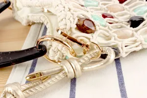 Vue détaillée d'un sac pour femme tissé de perles avec pierres colorées et fermoir métallique.
