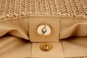 Detailed closeup view of women woven straw bag khaki interior with metal magnetic snap