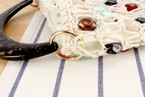 Gros-plan sur le détail du sac tissé avec des pierres colorées et poignée en résine.