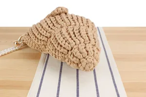 Handmade chunky knit crochet handbag detail, stylish beige casual design with pearl strap.