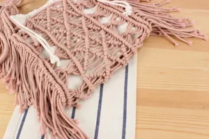 Closeup of handmade pink macrame fringe shoulder bag detail, boho style summer beach vacation.