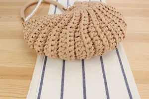 Handmade beige crochet handbag detail, stylish woven texture with elegant pearl handle.
