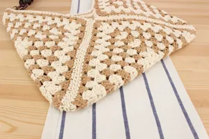 Close-up detail of the handmade crochet shoulder bag with beige brown granny square pattern.