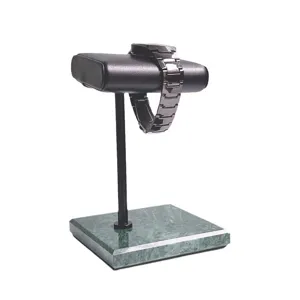 Groene marmeren horlogestandaard met zwarte metalen stang en kussen voor winkeldisplay.