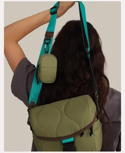 Detail view of the green quilted camera bag with adjustable turquoise strap and mini pouch.