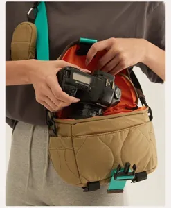 Quilted lightweight camera bag with adjustable teal strap and orange lining for travel.