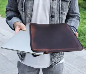 Vista detallada de funda para portátil de cuero marrón, textura interior suave y cremallera.